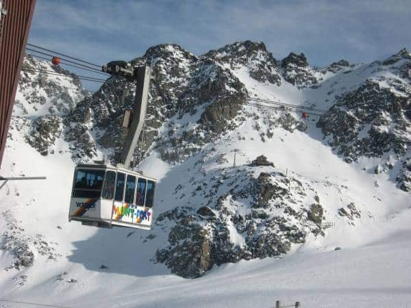 Majestic snow-capped peaks, ski gondola gliding up the slopes in winter wonderland.