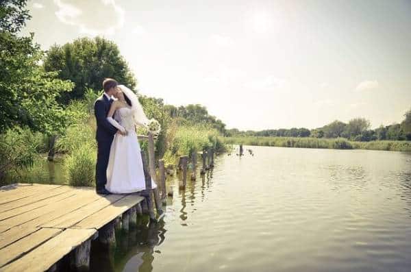 Couples intimate moment on tranquil wooden dock surrounded by nature.