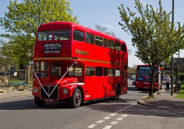 Classic red London double-decker bus in scenic urban setting.
